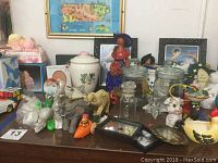 Overview of assorted animal figurines, urns, ceramic statues, and souvenir items arranged on a table.
