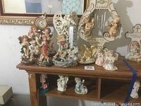 Full view of the 12 figurines arranged on a wooden shelf including angels and cherubim of various sizes and designs