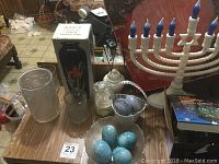 Overview of assorted items on a table including candle holder, marble eggs in glass basket, glass candle holder, and boxed candy box