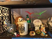 Front view of the lot showing elephant clock, German beer stein, leprechaun figurine, bird sculptures, and other animal decor