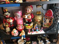 Wide view of shelf displaying various circus decor items including clown figurines, jars, and musical boxes.