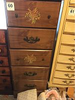 Front view of vintage wooden dresser showing 5 drawers including two with inlaid wheat design and varied drawer handles.