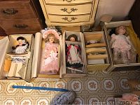 Five porcelain dolls in original boxes, showing varying styles and packaging.