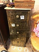 Full front view of tall narrow cabinet showing five drawers with ornate knobs and distressed metallic look finish.