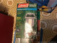 Coleman Outdoor Series Floating Lantern in original box featuring floating and high impact base properties on tile floor.