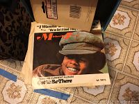Photo showing a 45 RPM record cover featuring an image of a smiling young person in a cap, text includes 'Michael Jackson', song titles, and album references from the 1970s era.