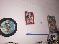 Wall clock and two Mickey Mouse themed wall art pieces displayed on white wall