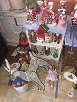 Shelf with assorted Christmas collectibles including figurines and toys, showing wear and paint chips on shelf