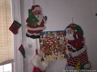 Photo of various hanging Christmas decorations on a wall including stockings, Santa figure, and advent calendar