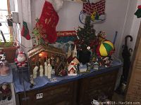 Overview of the nativity set and various Christmas decorations arranged on a cabinet with a blue cloth beneath