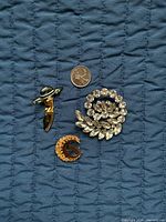 Front view of the three brooches with quarter for scale