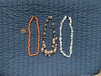All three necklaces side by side with coin for scale