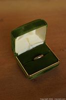 Ring in open green velvet box showing band profile