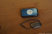 Closed cigarette case beside brandy tag on chain