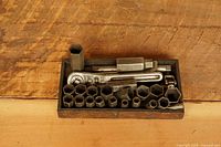 Full view of wooden tray with ratchet, extension, large socket and multiple smaller sockets