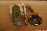 Willson spectacle case, thermometer, brass buzzer with cord on wood surface