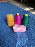 Four thread cones grouped on quilted surface