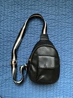 Front view of black crossbody bag showing pocket, body, and strap