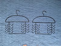 Two identical black metal accessory hangers on blue background