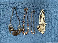 All four necklaces laid out side by side on blue background