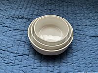 Three nested white stoneware bowls on quilt
