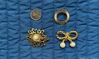 overview of all three brooches with coin for scale