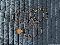 All three pairs of hoop earrings beside penny for scale