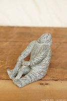 Full view of Inuit stone sculpture showing seated pose and frame