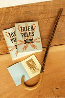 Lot overview showing two Totem Poles books, open Franz Johnston booklet with photo, and painted wooden cane