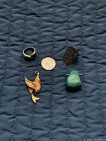 All four jewelry pieces with coin for scale