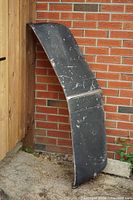 Full view of black-painted side of visor leaning against wall