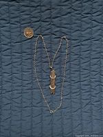Full view of necklace with pendant and coin for scale