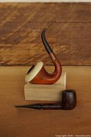 Calabash pipe on wood block and one straight briar pipe