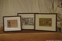 All three framed items—two photographs and one advertisement—displayed upright