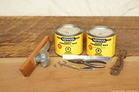 Lot overview showing two sealed Minwax wax tins, wooden feather board, pliers, scissors, rule and leather strap