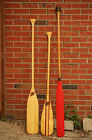 three wooden paddles leaning against brick wall