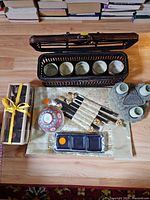 Overall lot showing wicker carrier, tea cups inside, chopsticks, bowl, candle holder, dish and boxed accessories
