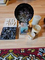 Group view showing all items: plate on stand, tile, tray of pebbles, five candles