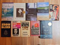 Group image showing at least ten paperback books laid out on wooden surface