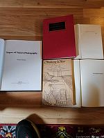 Group of the four clothbound books, two opened to show pages