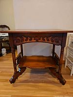 Front view showing carved apron, turned legs, lower shelf