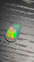 Pear-shaped opal on black background showing vivid play-of-color