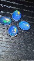 Four oval crystal jelly opal cabochons on black background