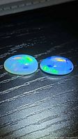 Both oval opals showing play-of-color on black surface