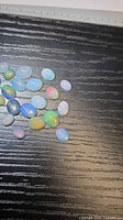 Group of oval opal cabochons on black surface