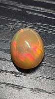 Top view of oval chocolate opal showing red and orange play-of-colour