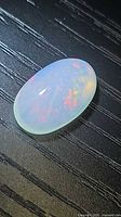 Top view of oval cabochon opal showing colour play