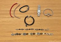 Overview of watch and seven bracelets laid out on wood surface