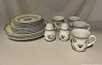 Full set showing stacked plates, four mugs, salt and pepper shakers