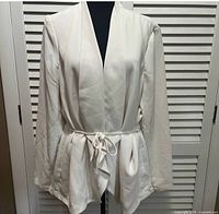 Front view of off-white Express blazer on mannequin showing open front and tie belt